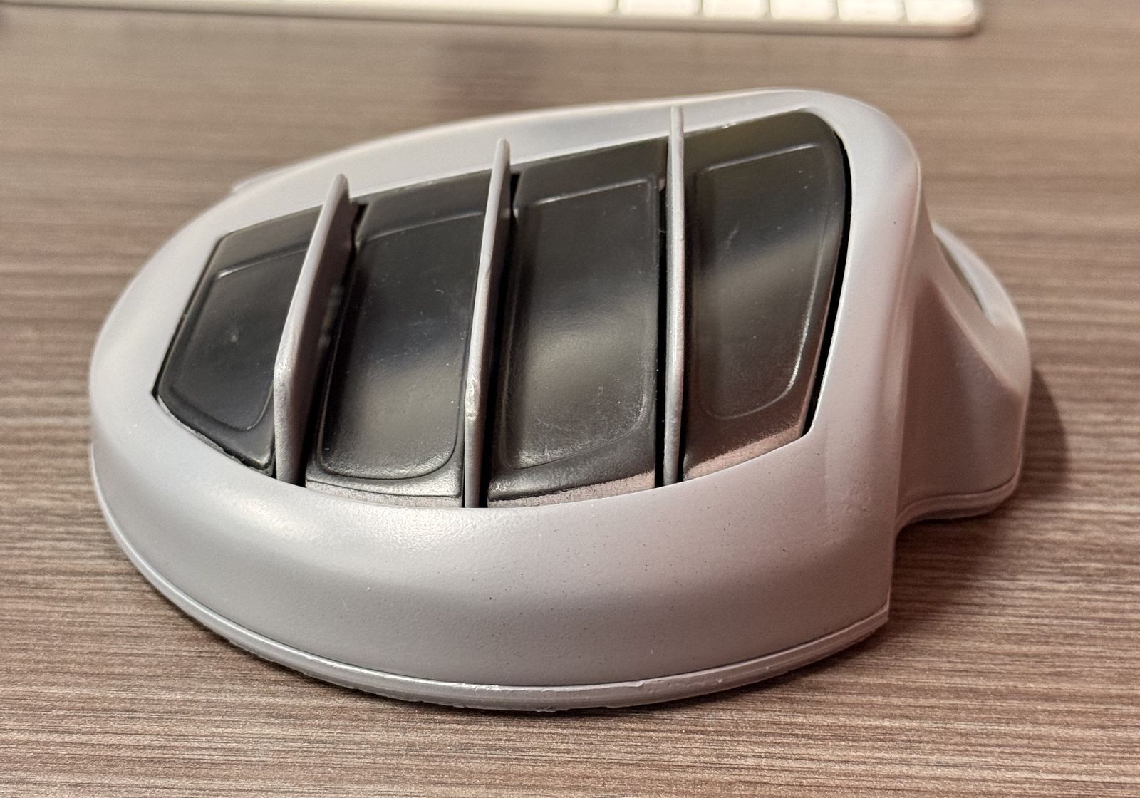 ErgoDigit Flex hand unit on a desk: a contoured grey hand rest with four finger keys and a thumb key on the side